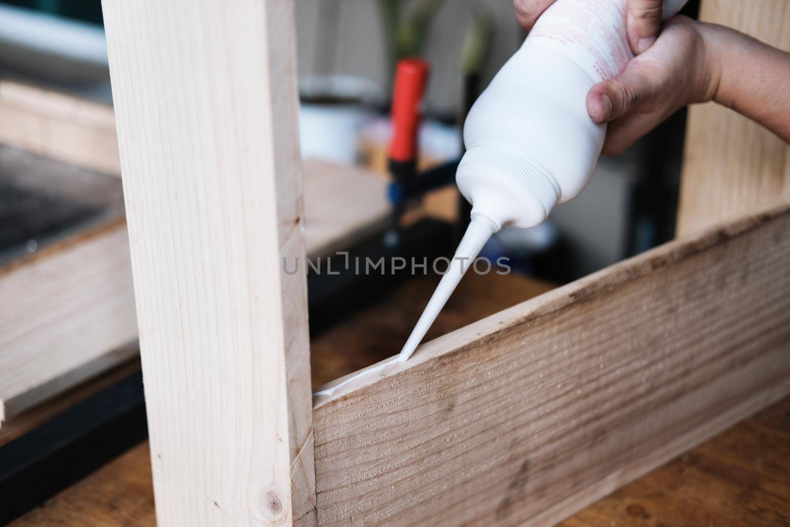 Woodworking operators are using glue to put together the wood parts to assemble and build a wooden table for their customers. by Manastrong