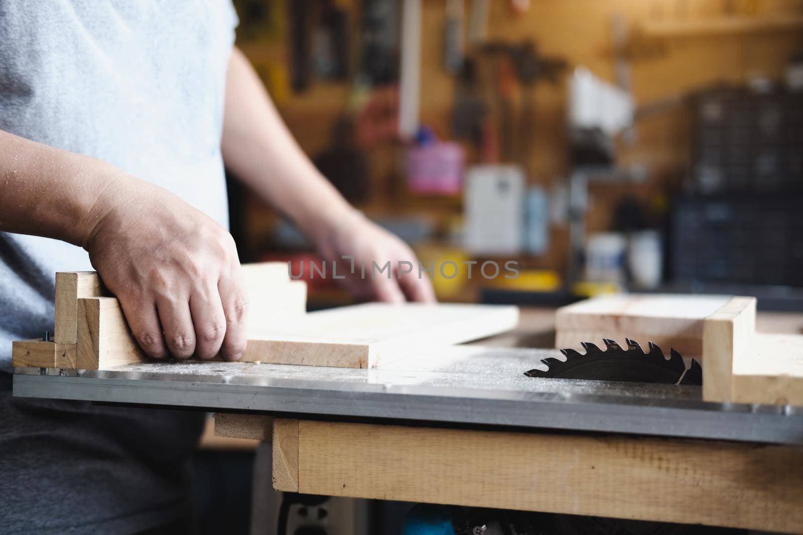 Woodworking practitioners use saw blades to cut wood pieces to assemble and build wooden tables for their clients. by Manastrong