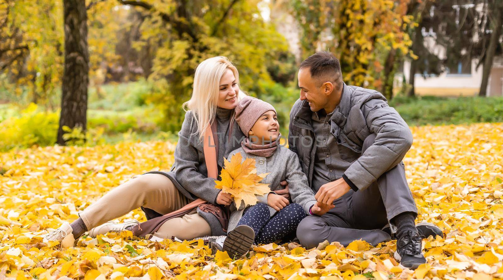 Young happy family while walking in the autumn park
