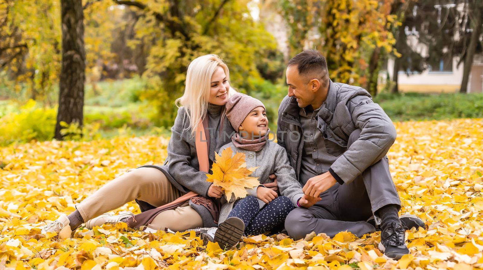 Young happy family while walking in the autumn park. by Andelov13