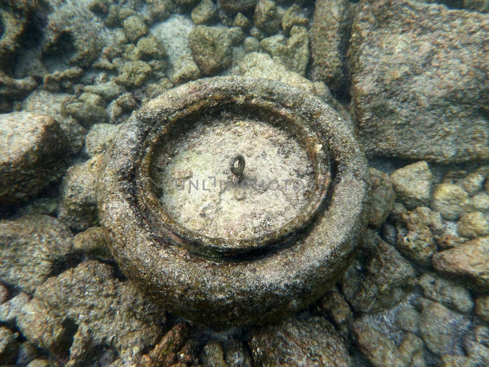 Old tire sits on top of sandy rocks underwater by EricGBVD