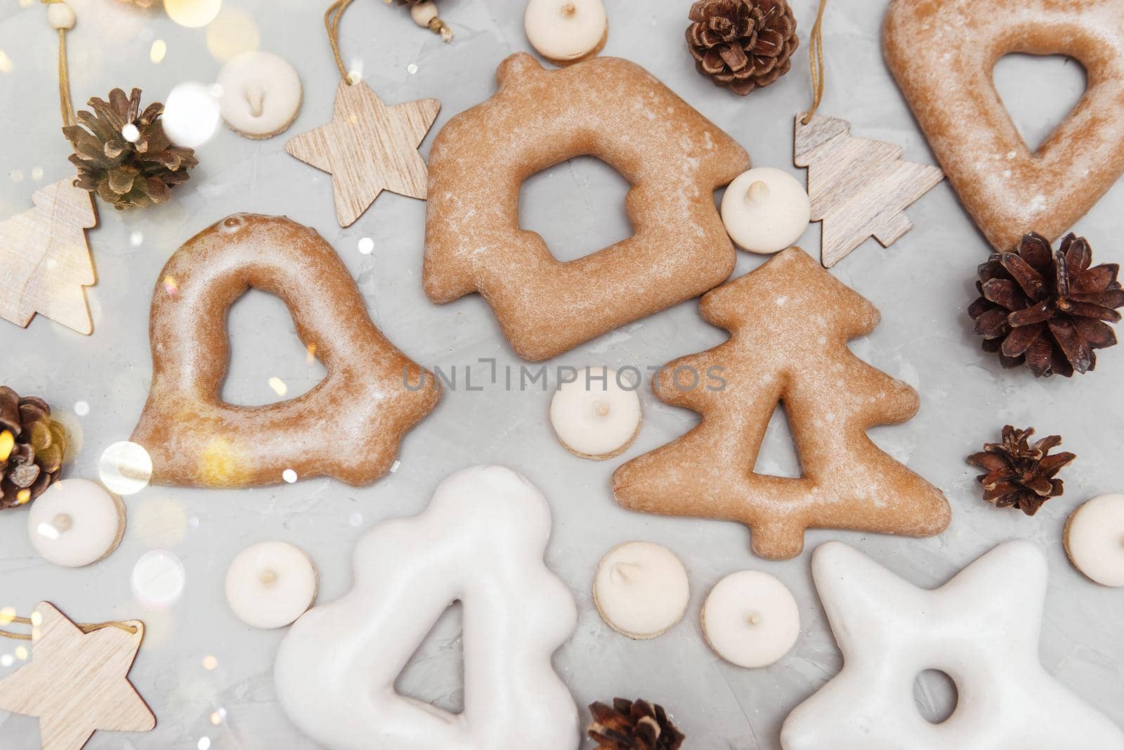 Banner for Christmas and New Year gingerbread stars, houses, Christmas trees, toys on a gray concrete background, Christmas lights bokeh in the foreground.