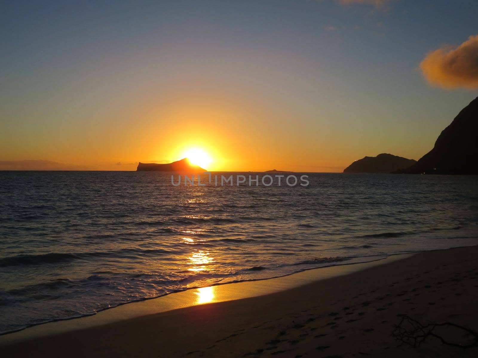 Early Morning Sunrise on Waimanalo Beach over Rabbit Island bursting over the island on Oahu, Hawaii.