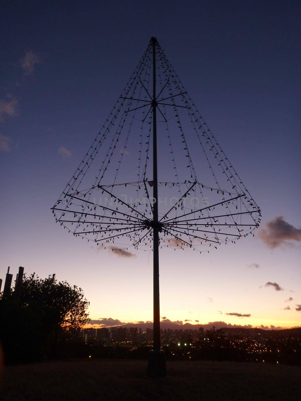  the Kaimuki Christmas tree (Metal Light Tree) on top Pu'u O Kaimuki (also known as Menehune Hill) at dusk on with cityscape of Oahu, Hawaii.