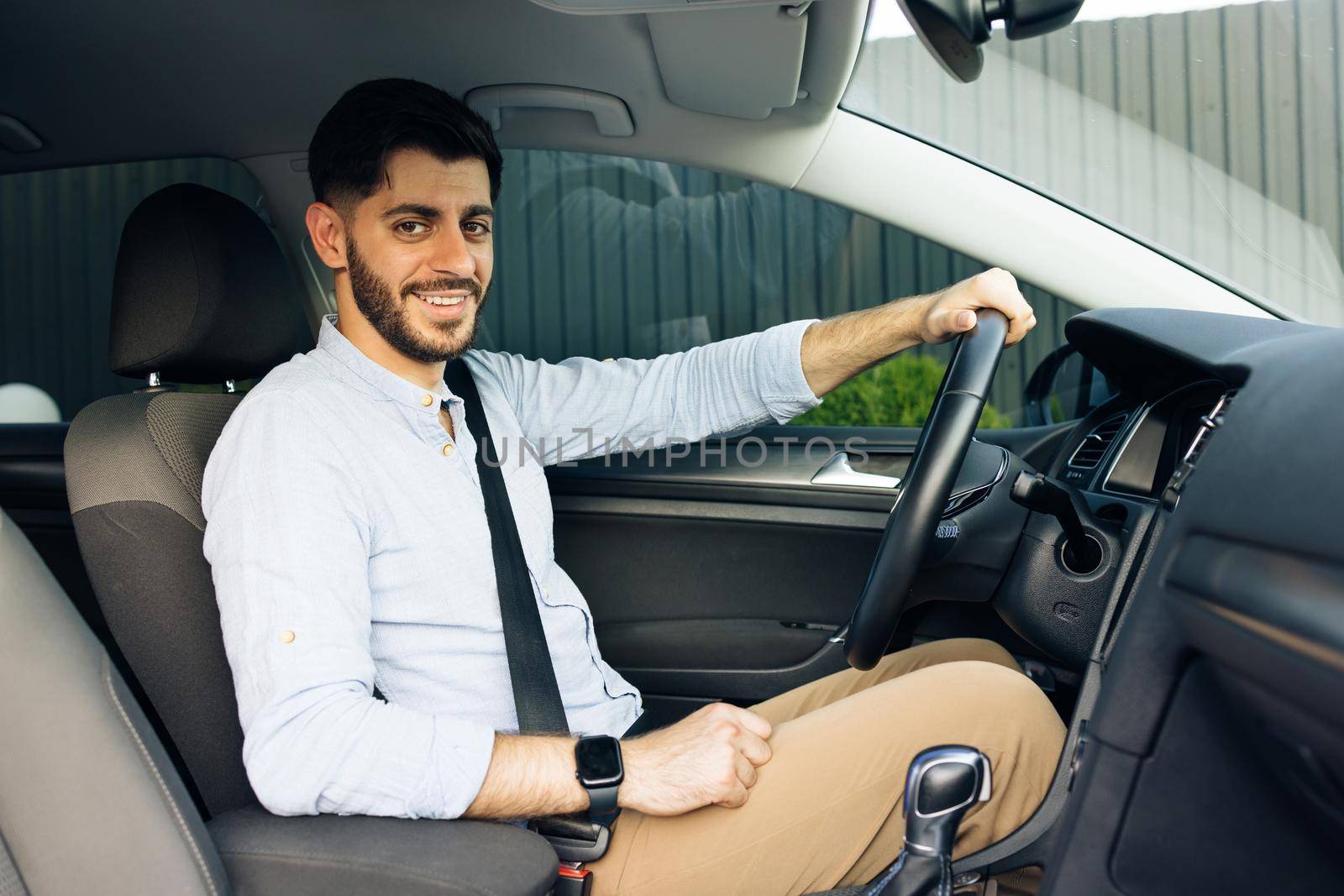 Portrait of caucasian bearded businessman driving car. cheerful man in his car looking camera. by uflypro