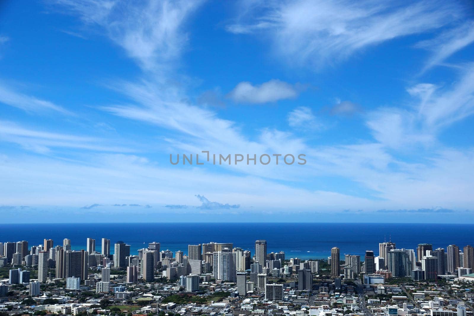 Waikiki and Honolulu cityscape, roads, buildings, skyscrapers, parks, and Pacific Ocean with boats in the water and clouds in the sky on Oahu, Hawaii. Metropolitan  