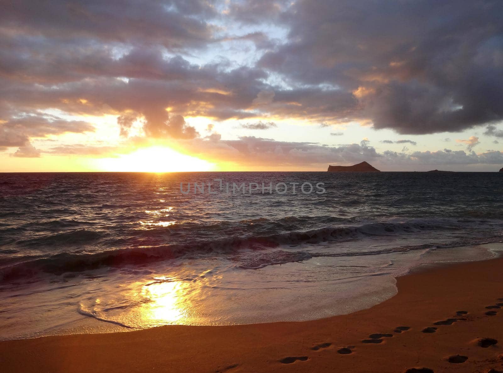 Early Morning Sunrise on Waimanalo Beach with sunlight reflection on the water and sand on Oahu, Hawaii with  rabbit and rock islands seen in the distance.