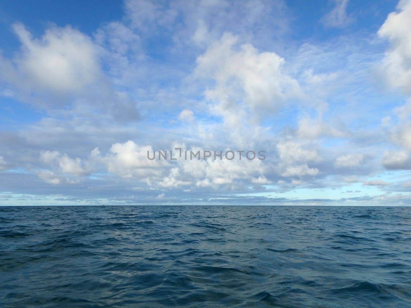 Shallow wavy ocean waters of Waimanalo bay looking into the pacific ocean with a blue sky full of clouds at dusk on Oahu.