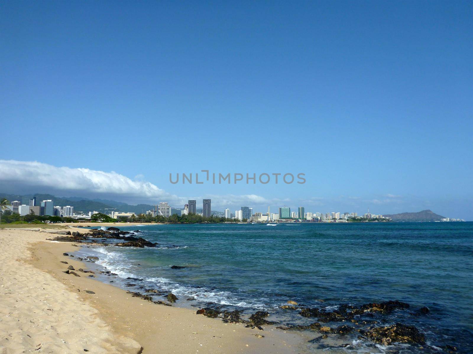 Sand Island beach off the coast of Oahu, Hawaii.  Featuring crashing waves and Honolulu, Waikiki in the background.