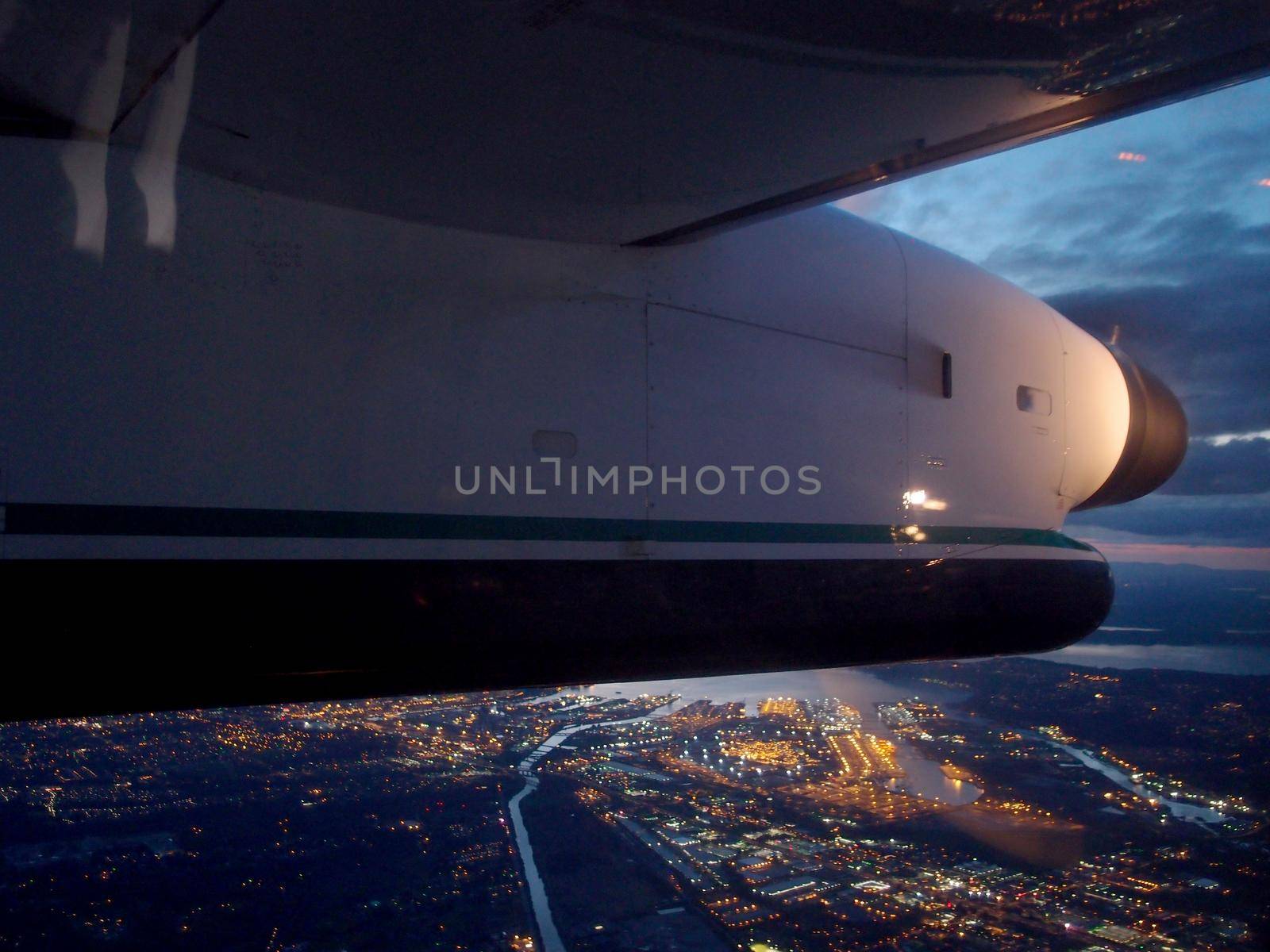 Plane Propeller Wing flies over City of Seattle, Washington at night.