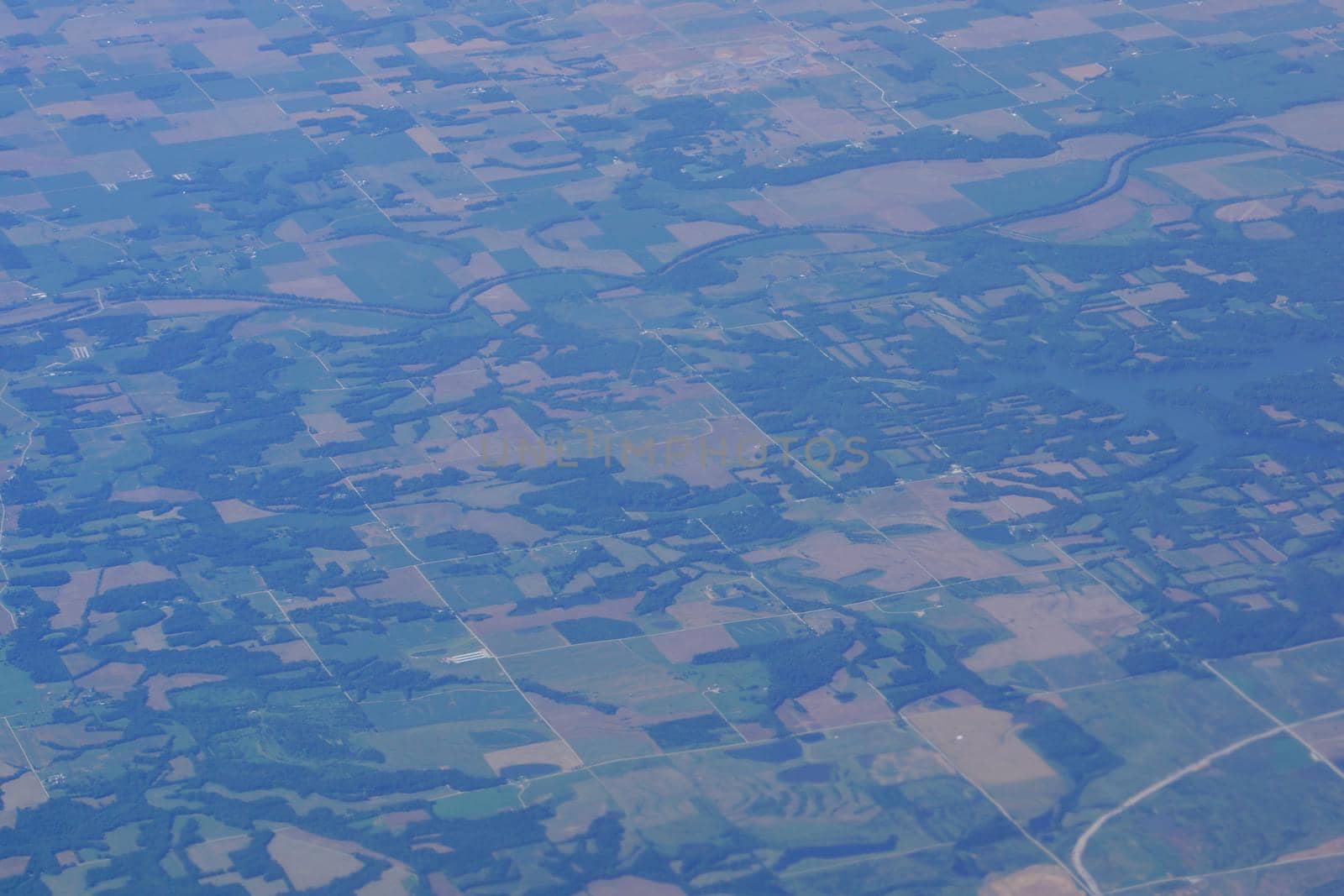 aerial photograph of rural Eastern USA with fields, river, houses, and roads from high above.