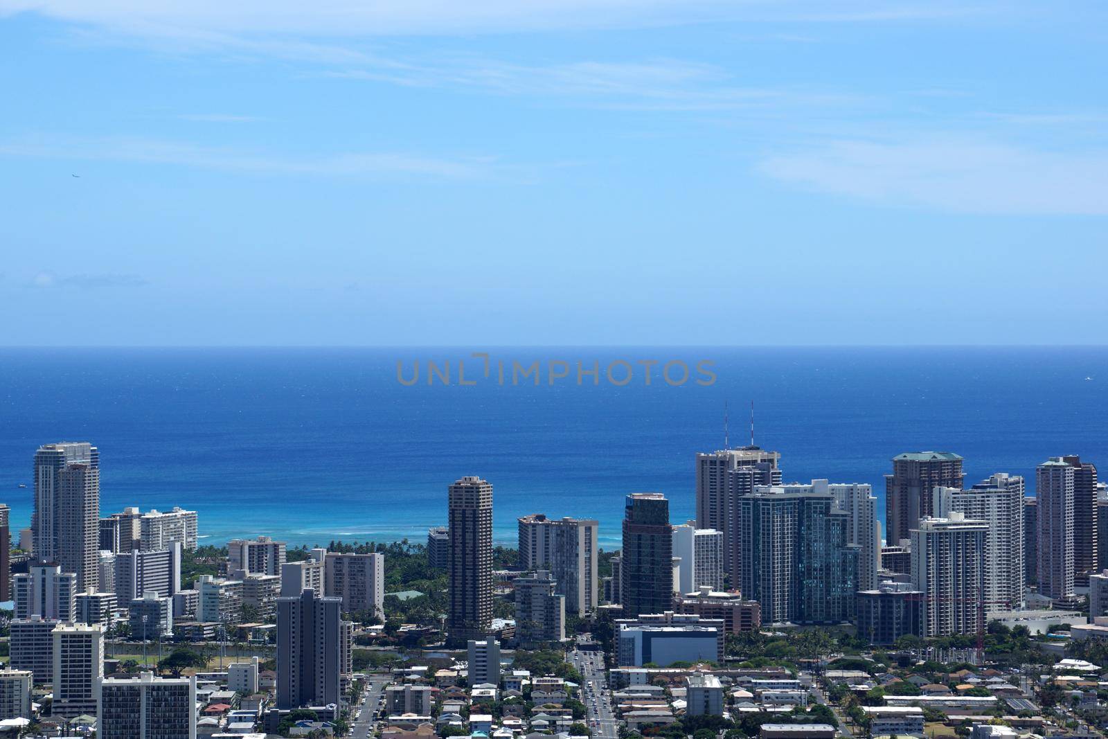 Waikiki and Honolulu cityscape, McCully street leading into Waikiki, roads, buildings, skyscrapers, parks, and Pacific Ocean with boats in the water and clouds in the sky on Oahu, Hawaii. Metropolitan.