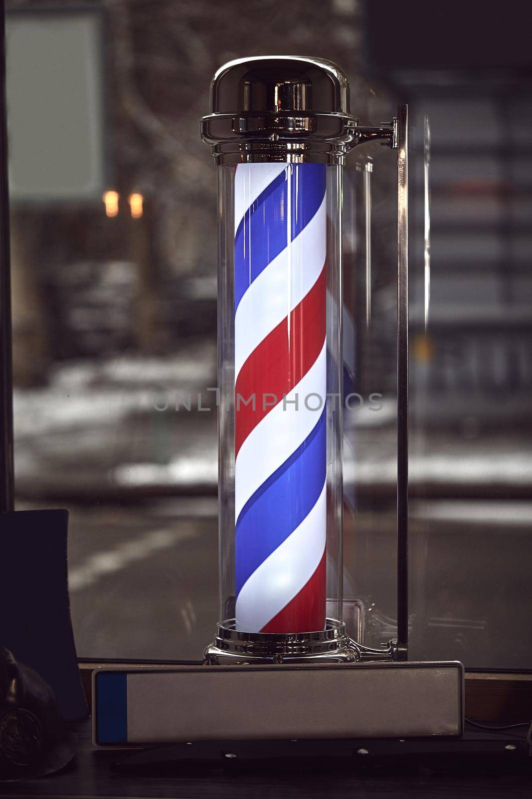 The famous symbol of a barber shop with it swirling red, blue and white stripes. by nazarovsergey