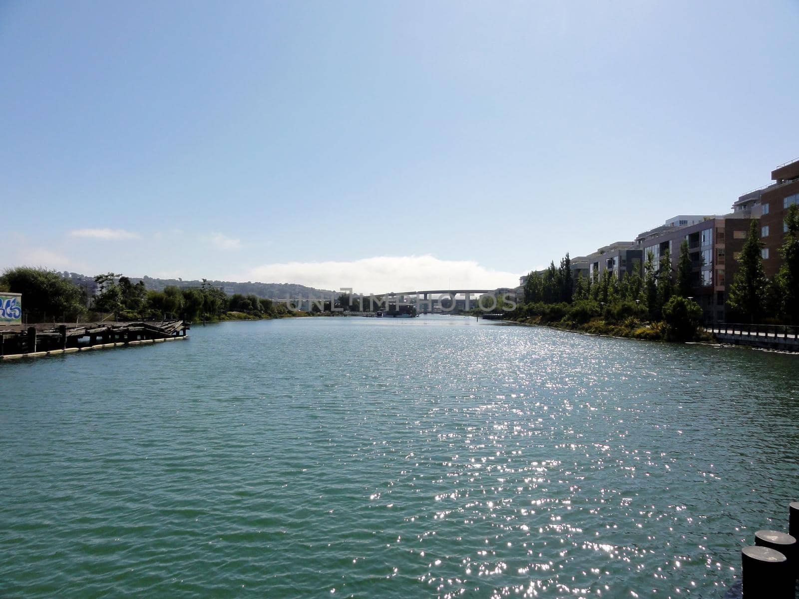 Mission Creek waterway with dilapidated pier and cars driving over raised highway in the distance on a nice day in San Francisco, California.