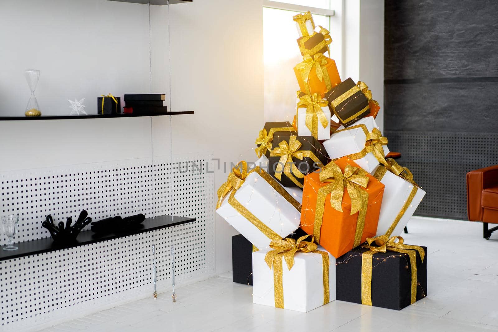 Christmas present gift box stacked on floor in living room white interior. Holiday sale concept. Many gift box black, white, orange color with gold ribbon