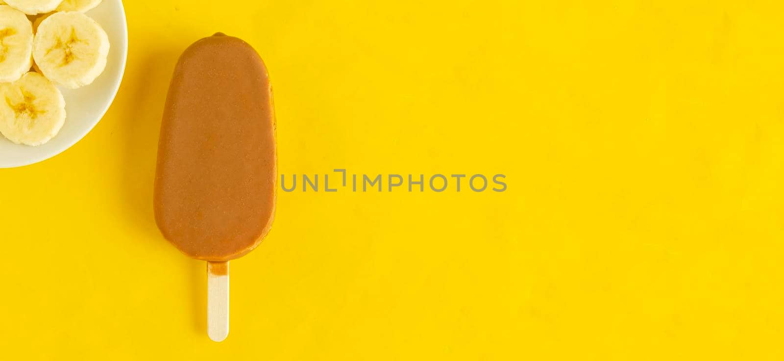 Banana vanilla popsicle in chocolated glaze on bright yellow background. by andre_dechapelle