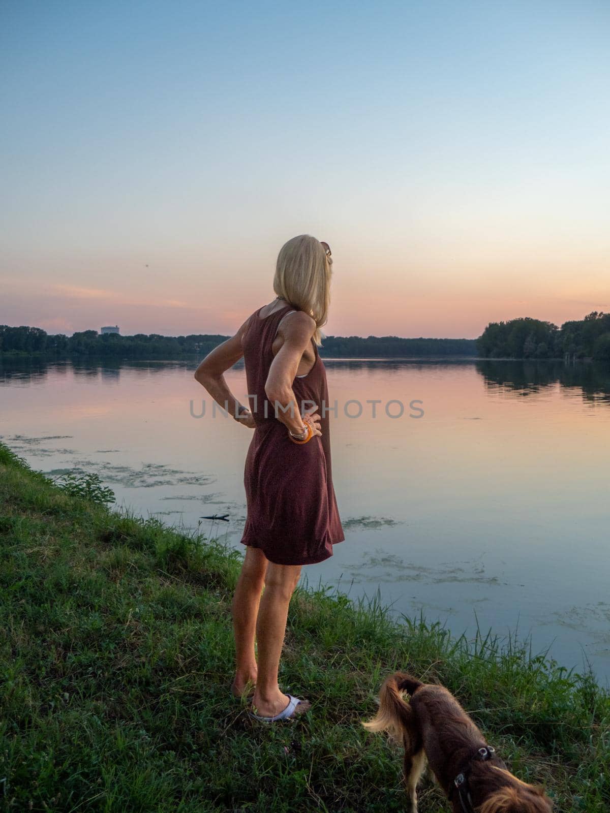 Beautiful woman enjoys holidays at sunset near river