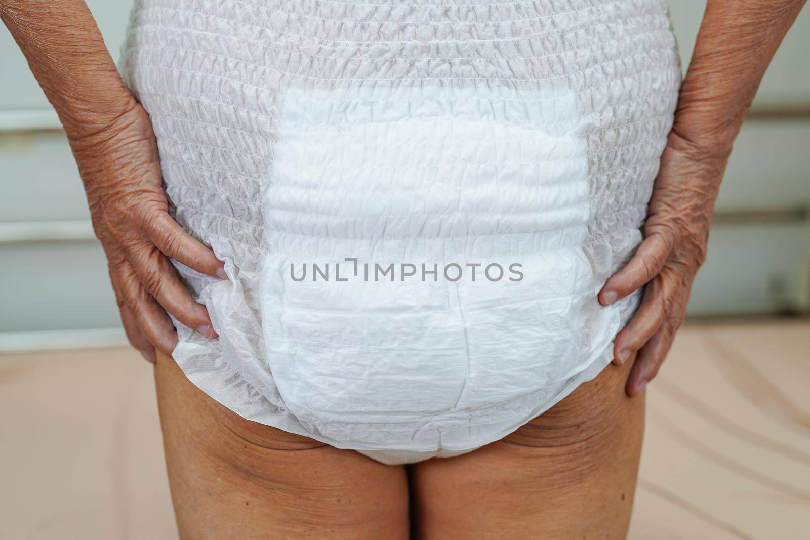 Asian elder senior woman patient wearing adult incontinence diaper pad in hospital.