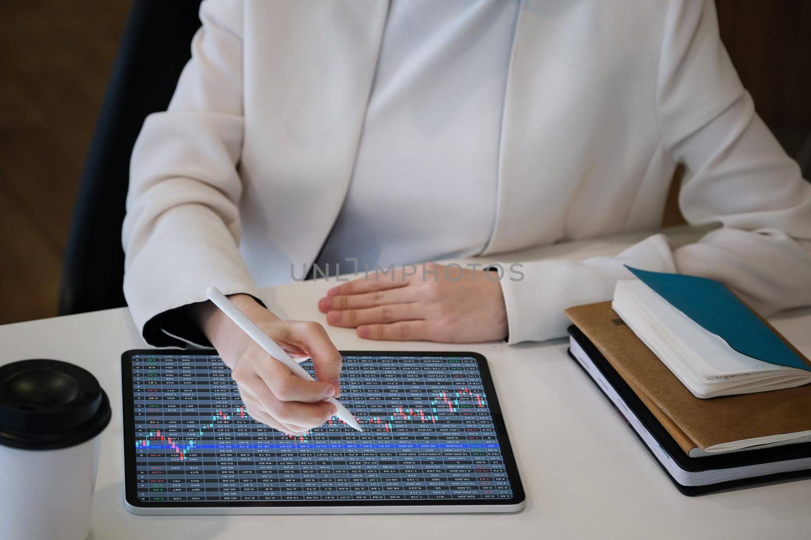 Business woman using tablet to trade charts to find buy and sell points for her port. by Manastrong