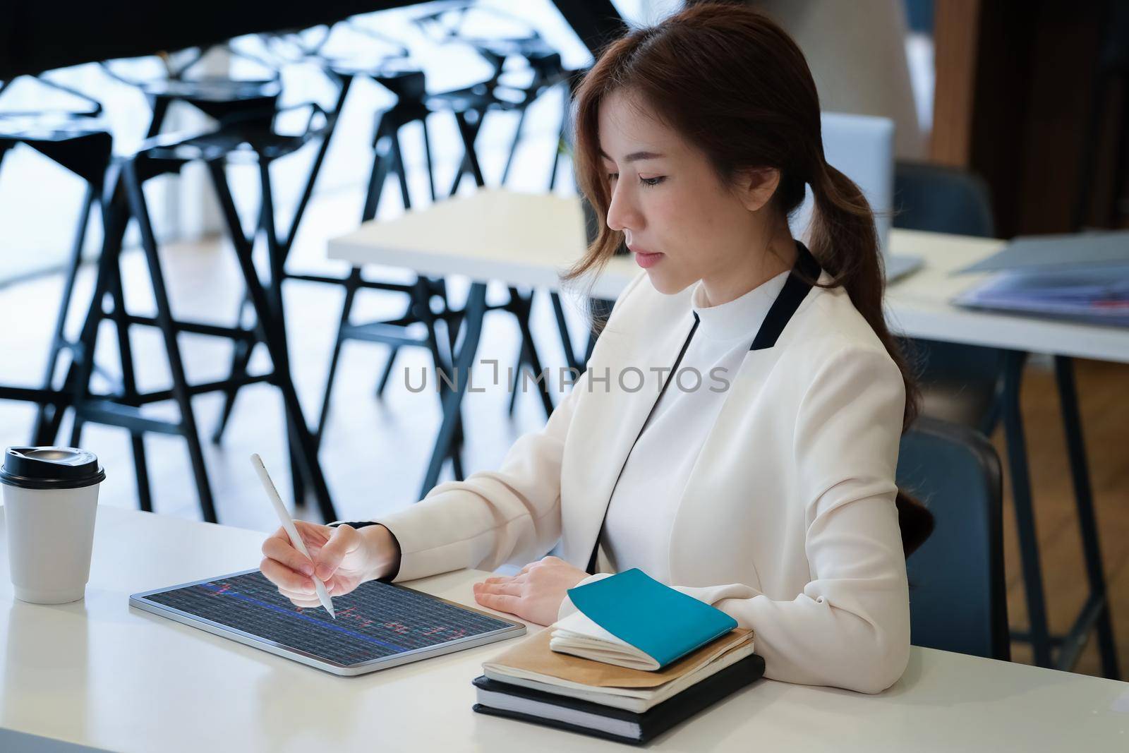 Business woman using tablet to trade charts to find buy and sell points for her port. by Manastrong