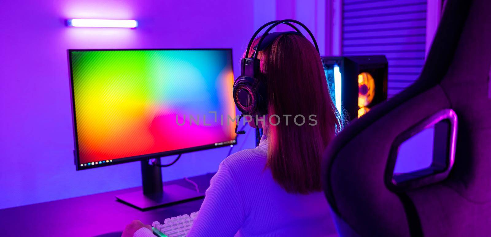 Asian professional gamer playing online video game on desktop computer PC have colorful neon LED lights by Sorapop