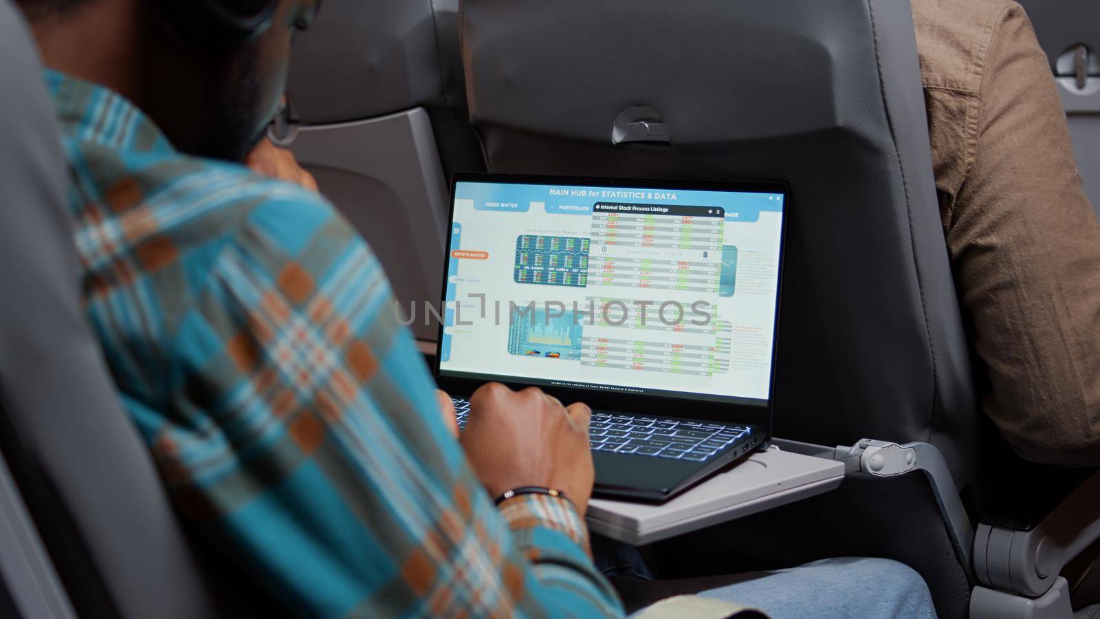 Hedge fund employee checking real time stock market statistics, flying in economy class. Travelling by airplane and looking at global trade exchange for financial investment on laptop. Close up.