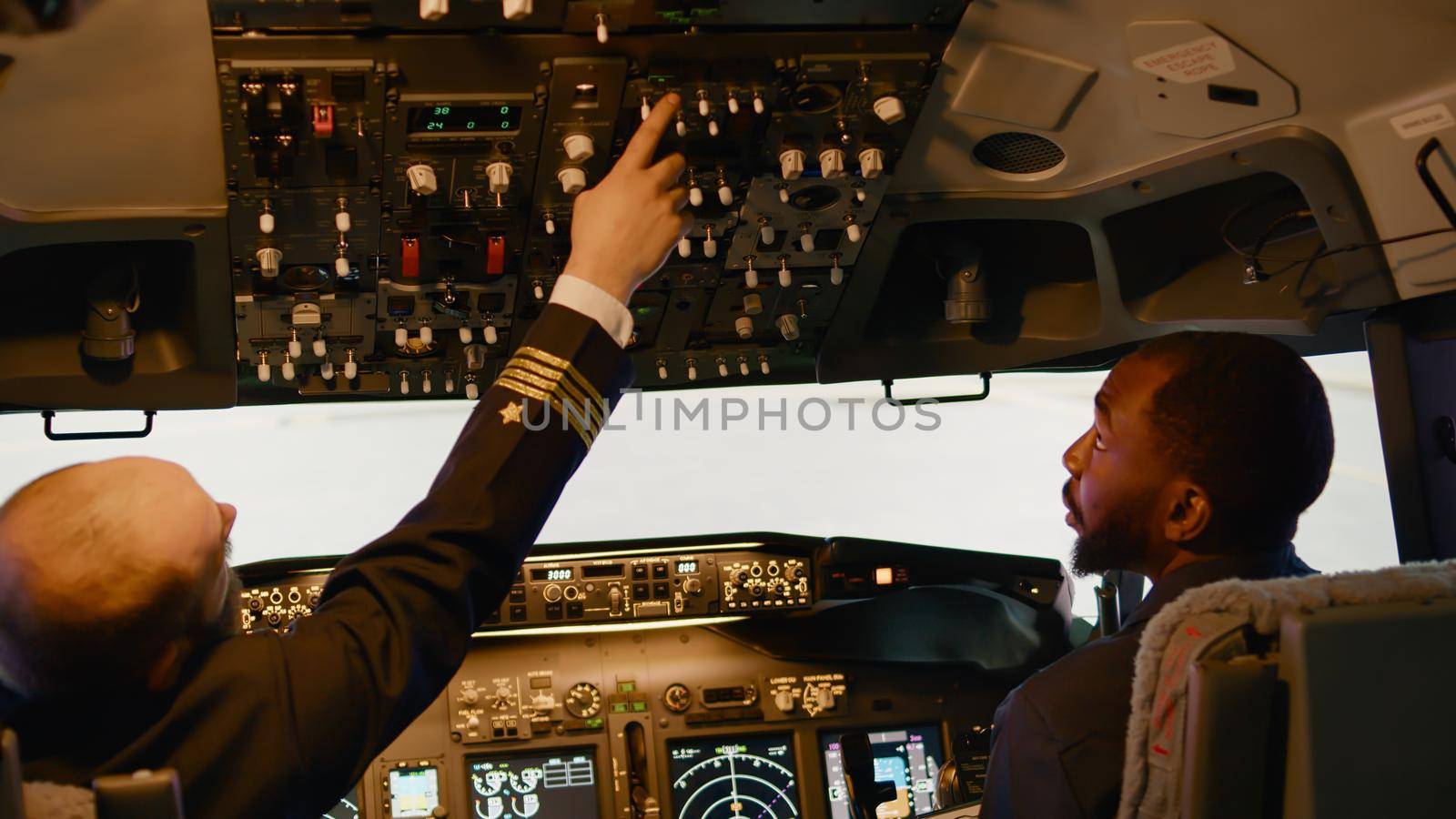 Team of diverse captain and copilot preparing to takeoff with airplane, pushing navigation buttons on dashboard command. Flying aircraft jet with power engine, using control panel.
