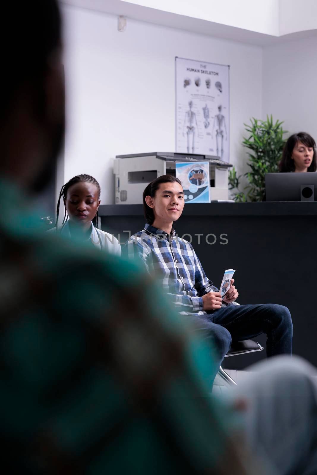 Selective focus on asian patient sitting down in hospital lobby waiting for doctor in private clinic by DCStudio