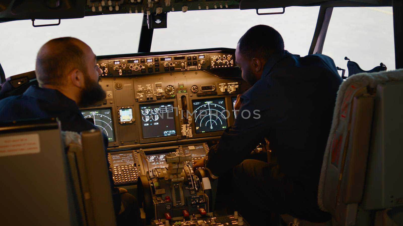 Diverse team of captain and copilot preparing to takeoff with airplane, inserting destination coordinates in cockpit control panel. Aircrew flying plane using dashboard command.
