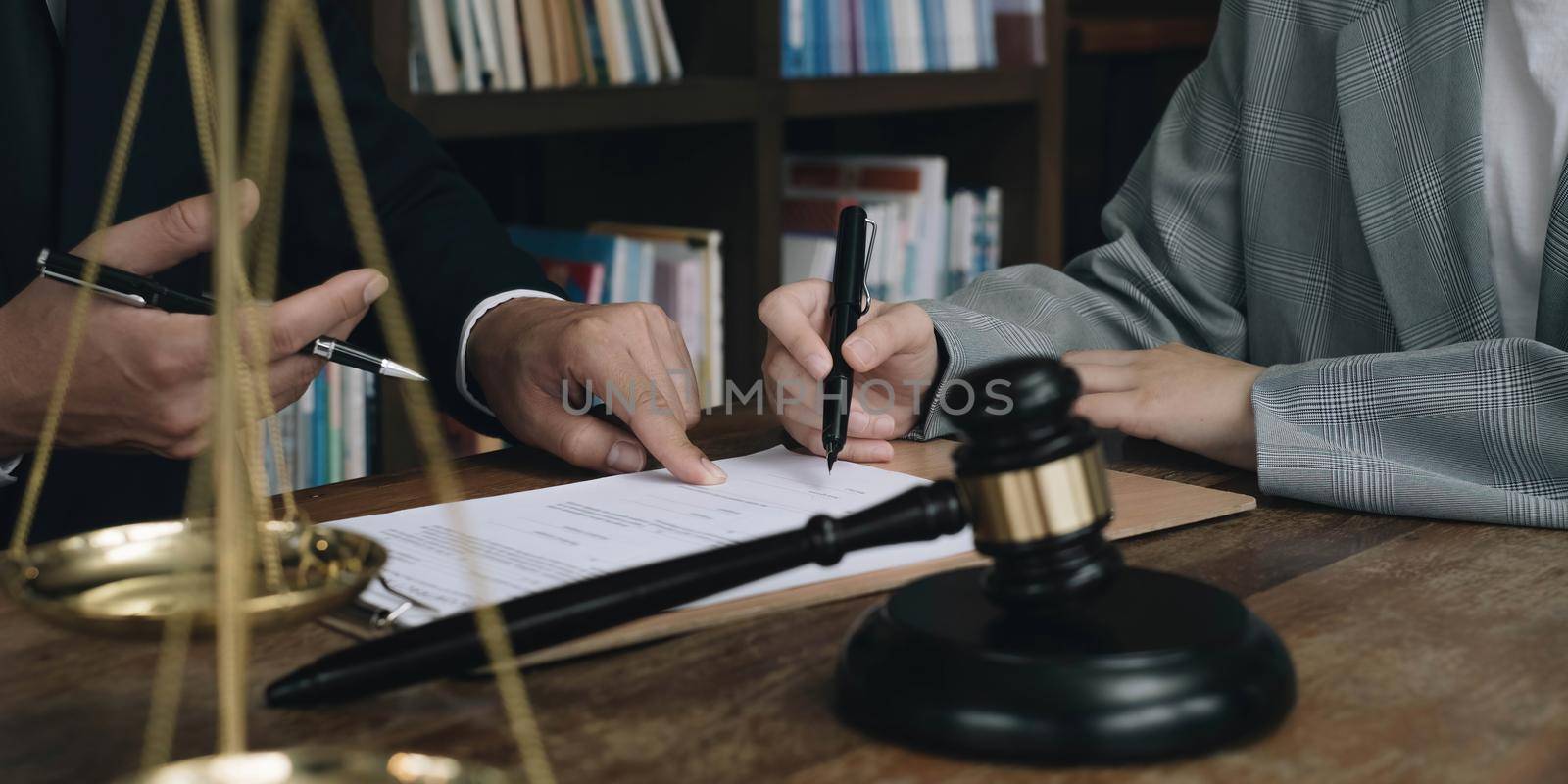 Business woman and lawyers discussing contract papers with brass scale on wooden desk in office. Law, legal services, advice, Justice concept by wichayada