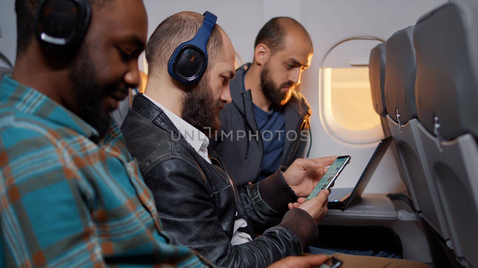 Freelancer using mobile phone during travel flight on plane, flying with international airline service. Travelling in economy class to go on holiday vacation, browsing website.