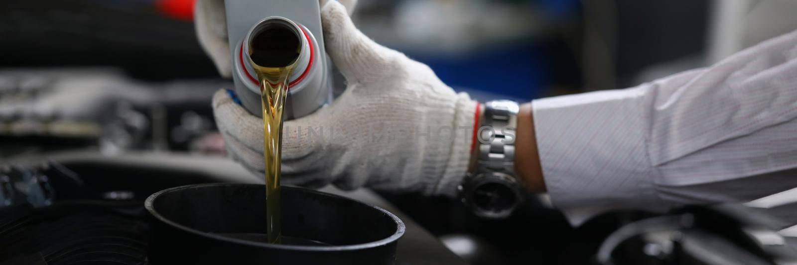 Close-up of worker refueling and pouring new oil into engine motor car. Mechanic from maintenance service fix transport. Maintenance gear, pit stop concept