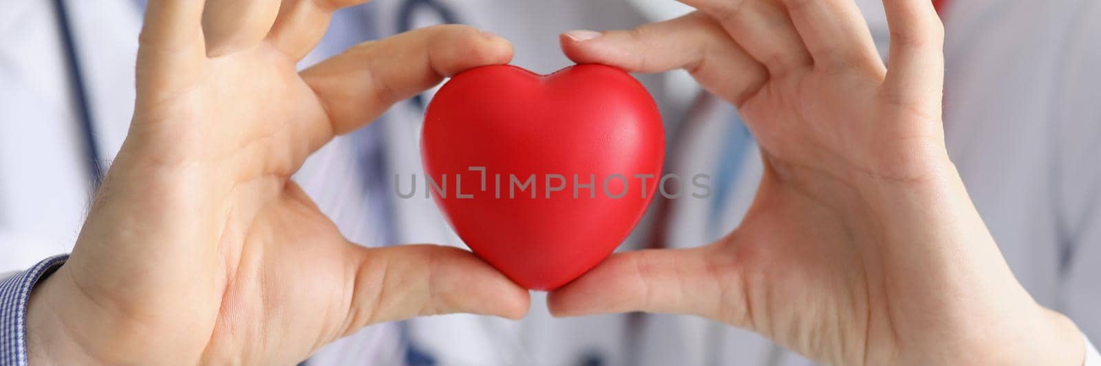 Medical workers colleagues together hold plastic red heart by kuprevich