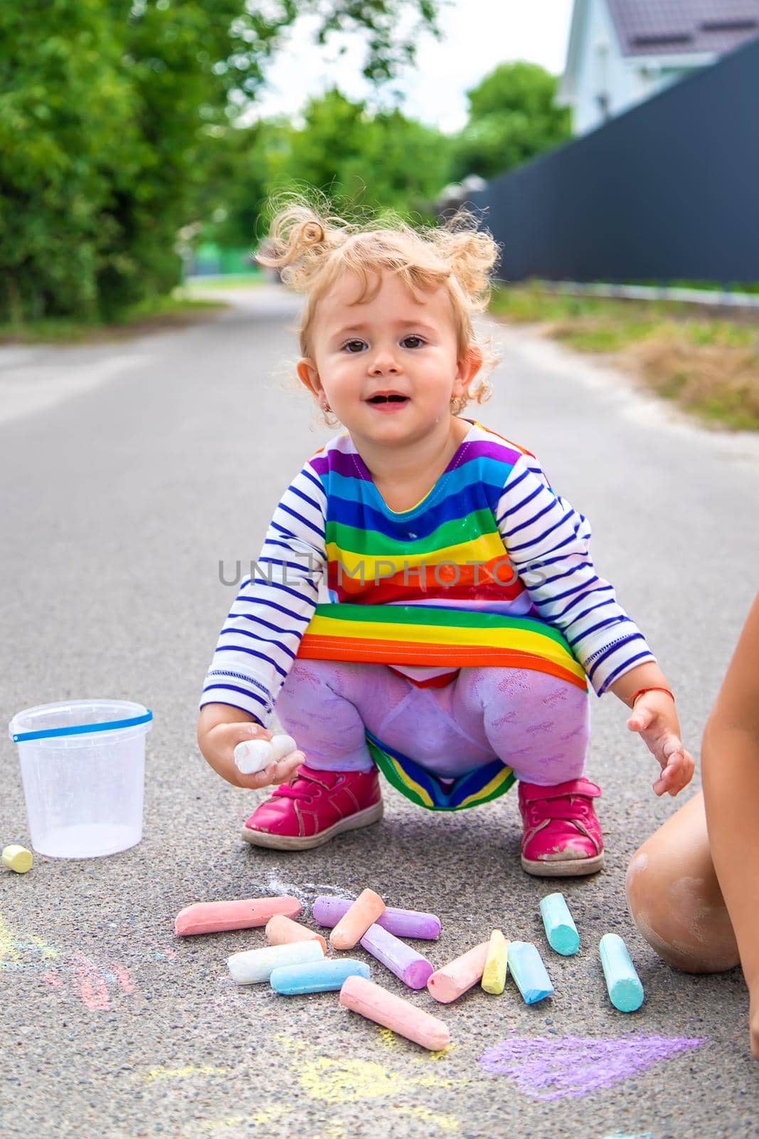 The child draws with chalk on the pavement. Selective focus. by yanadjana