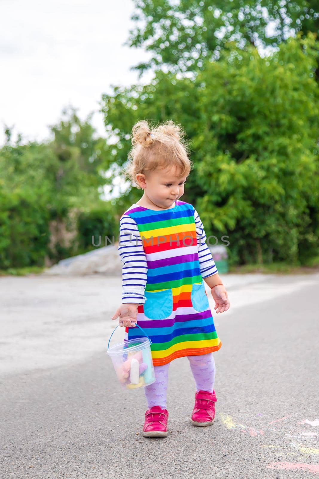 The child draws with chalk on the pavement. Selective focus. by yanadjana