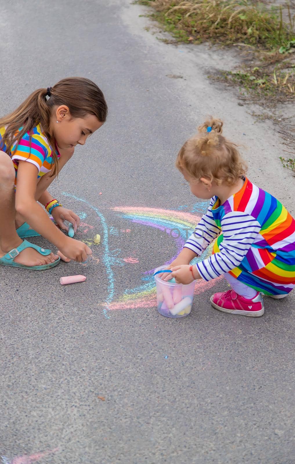 The child draws with chalk on the pavement. Selective focus. Kid.
