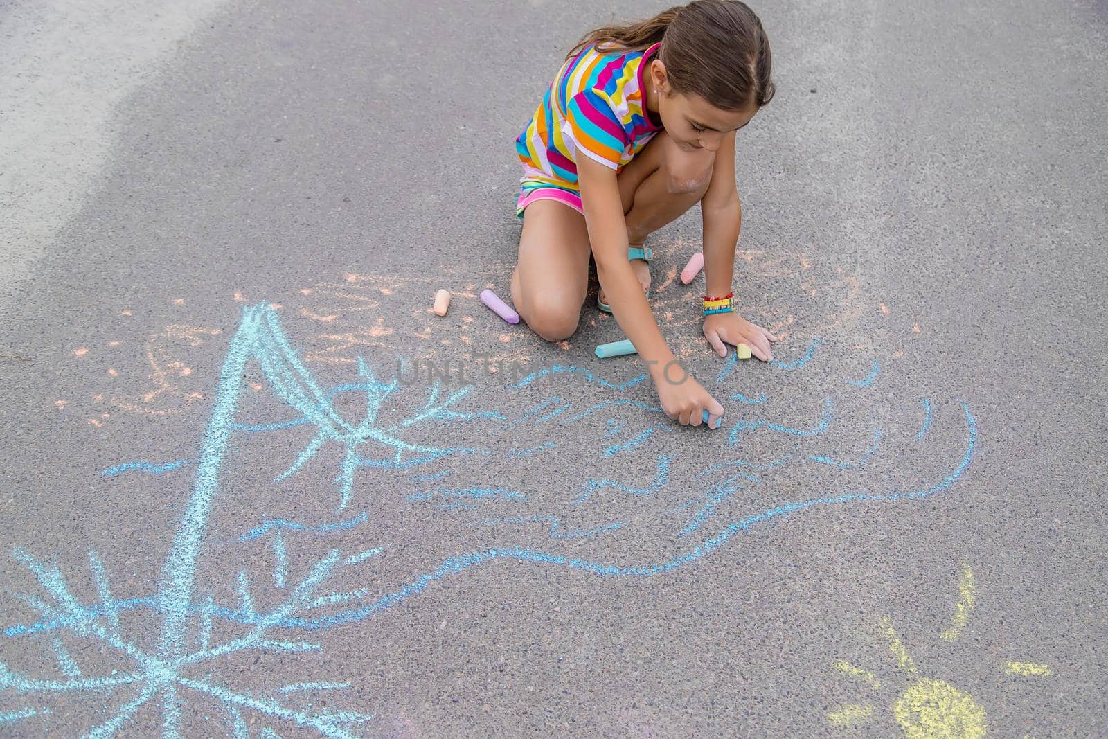 The child draws with chalk on the pavement. Selective focus. by yanadjana