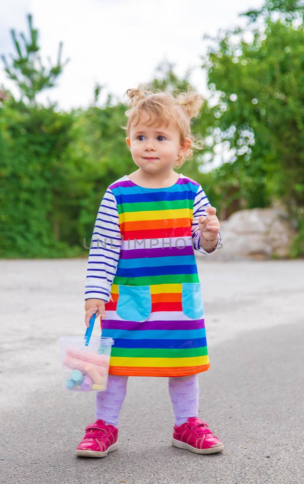 The child draws with chalk on the pavement. Selective focus. by yanadjana