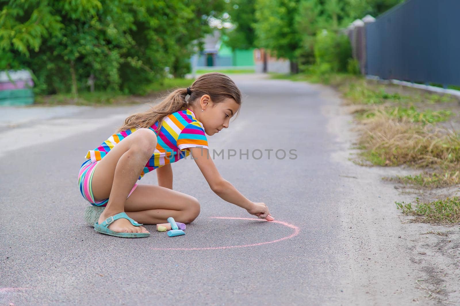 The child draws with chalk on the pavement. Selective focus. by yanadjana