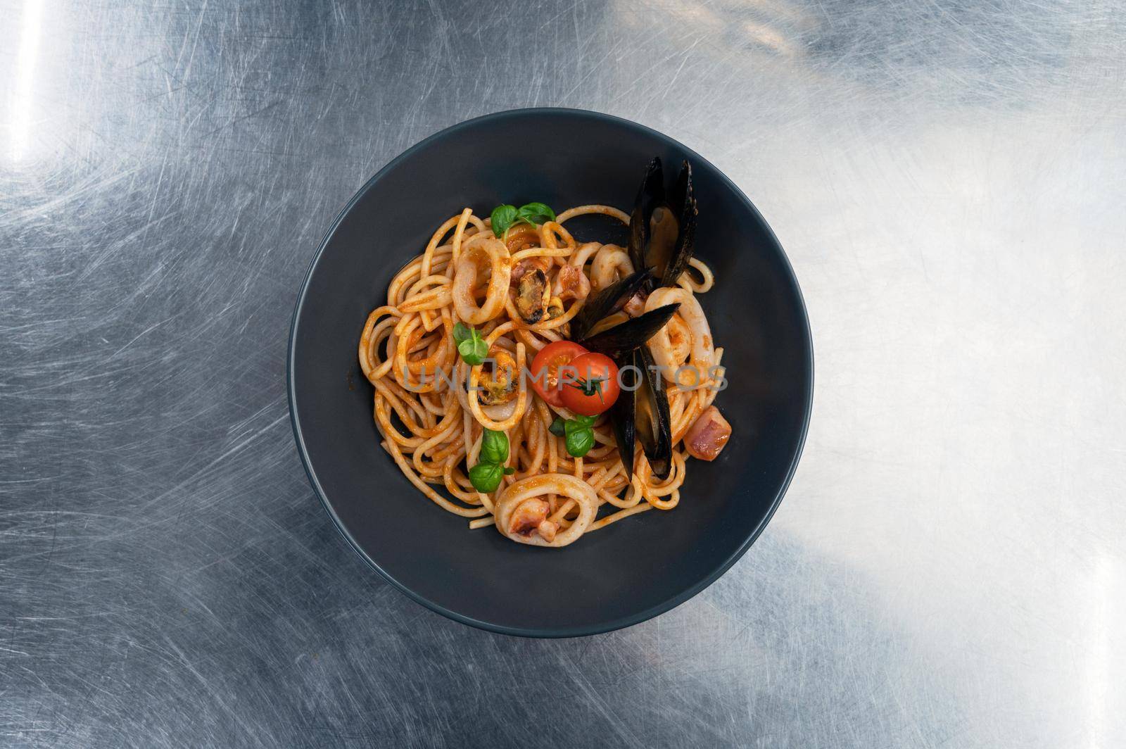 Seafood Pasta with mussels with basil and tomato in black plate