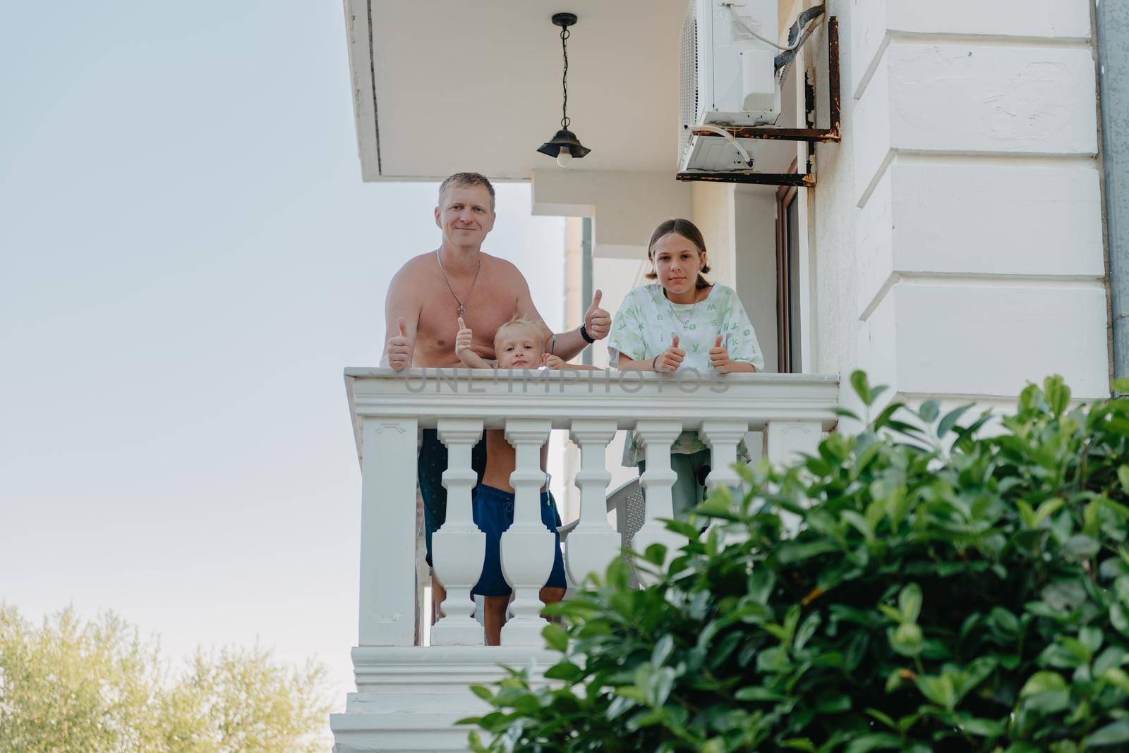 Family of three people on hotel balcony in summer enjoying their vacation.