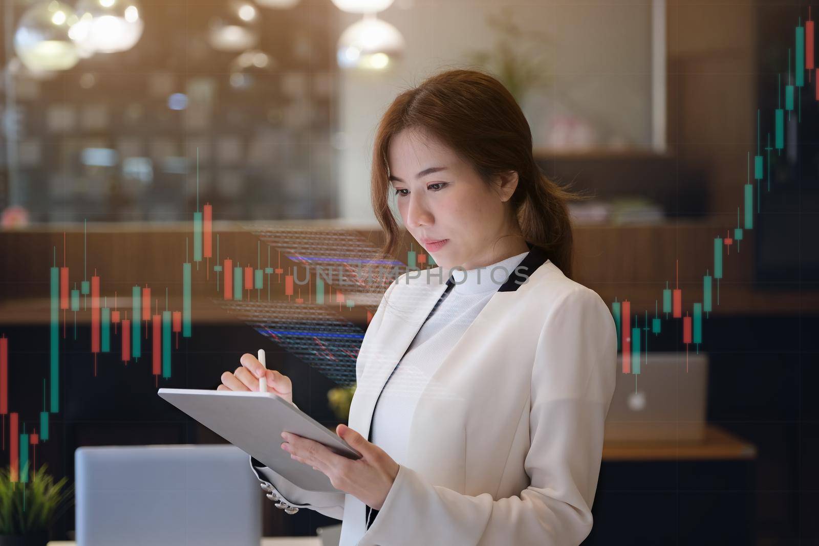 Business woman using tablet to trade charts to find buy and sell points for her port. by Manastrong