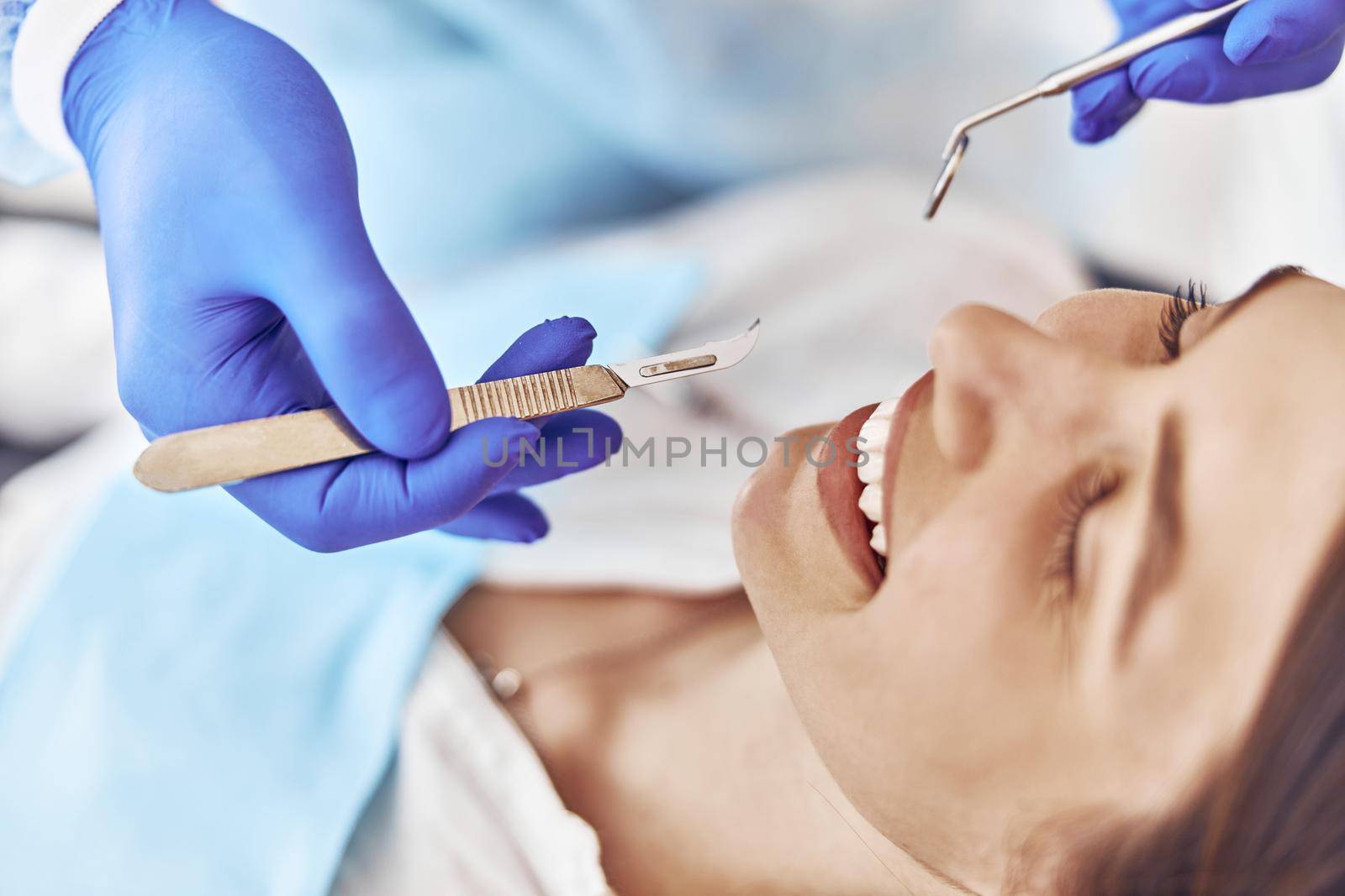 Professional doctor is doing tooth surgery to happy caucasian woman in modern dental cabinet
