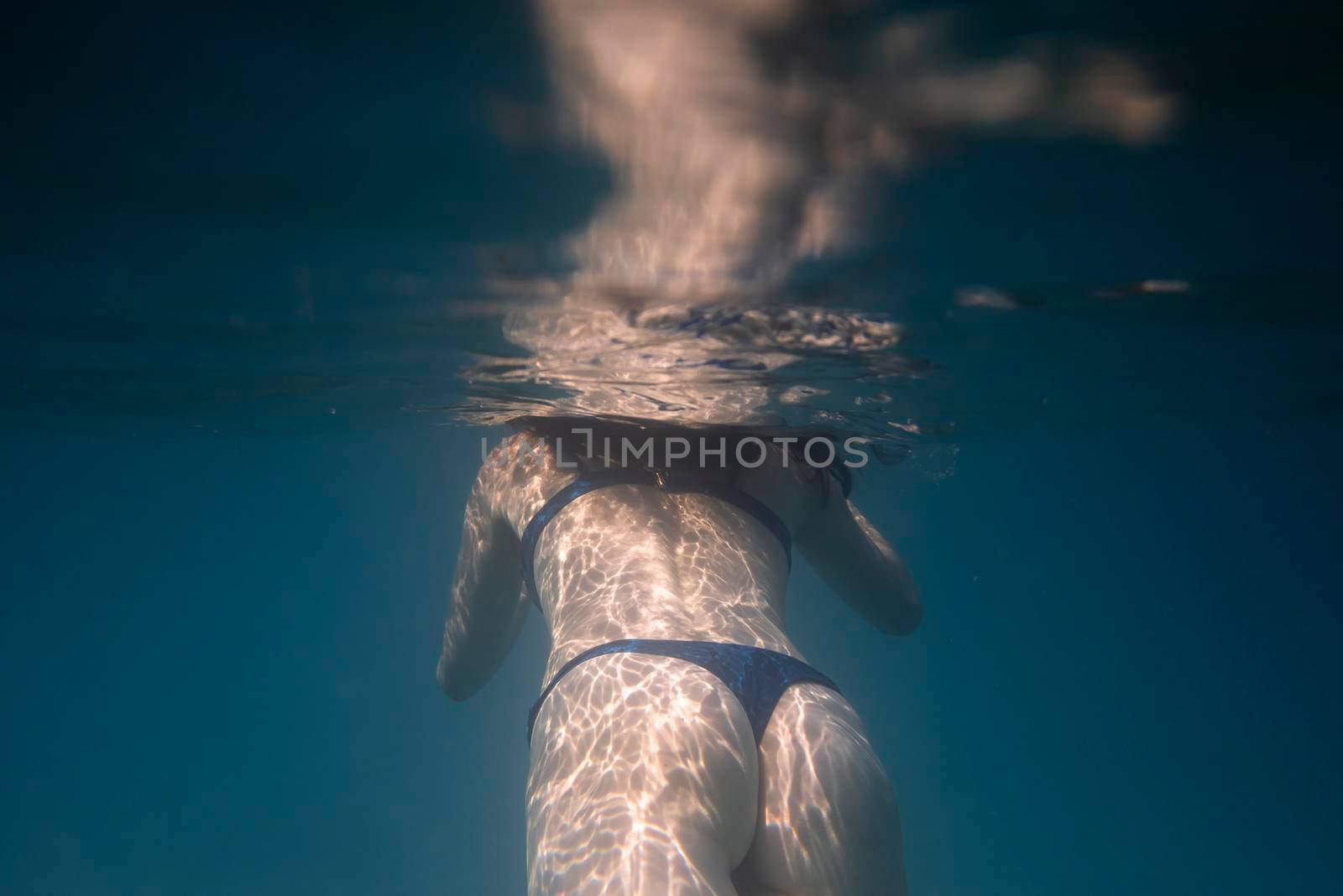 Woman swimming underwater in the ocean by SimmiSimons