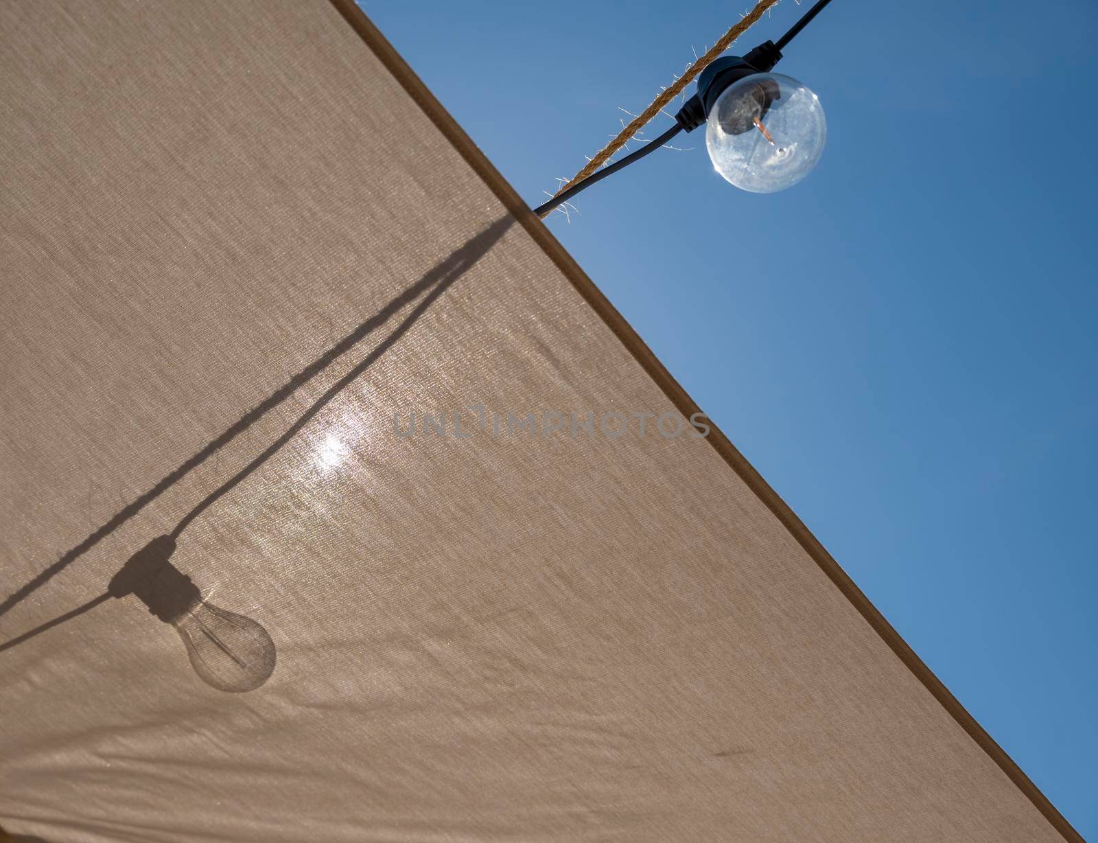 Light Bulb on tent creating shadow against the sun. Energy and ecological transition concept.
