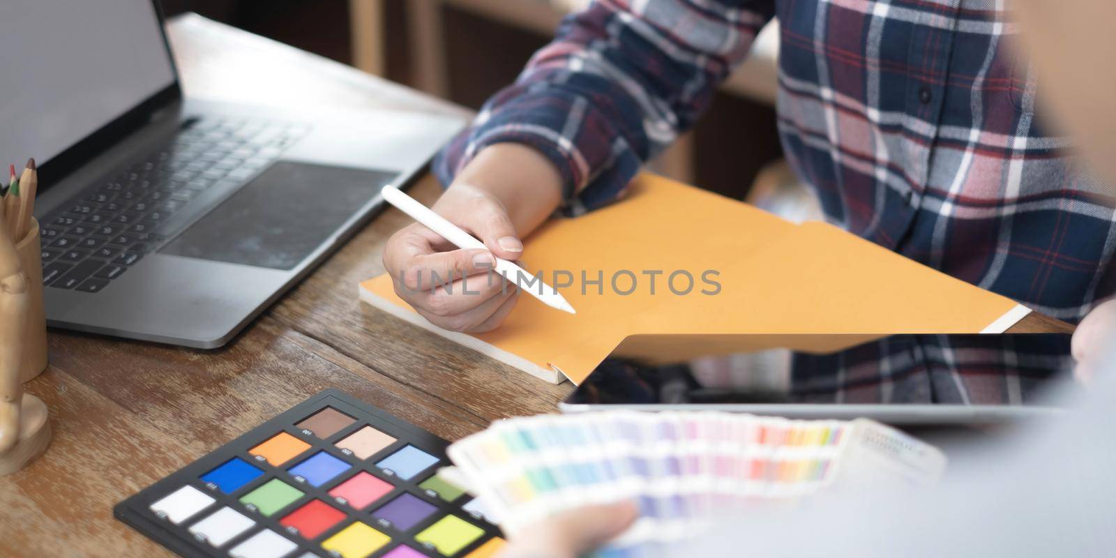 Team of creative graphic designer working on color swatch samples chart for selection coloring in inspiration to create new collection at workplace by wichayada