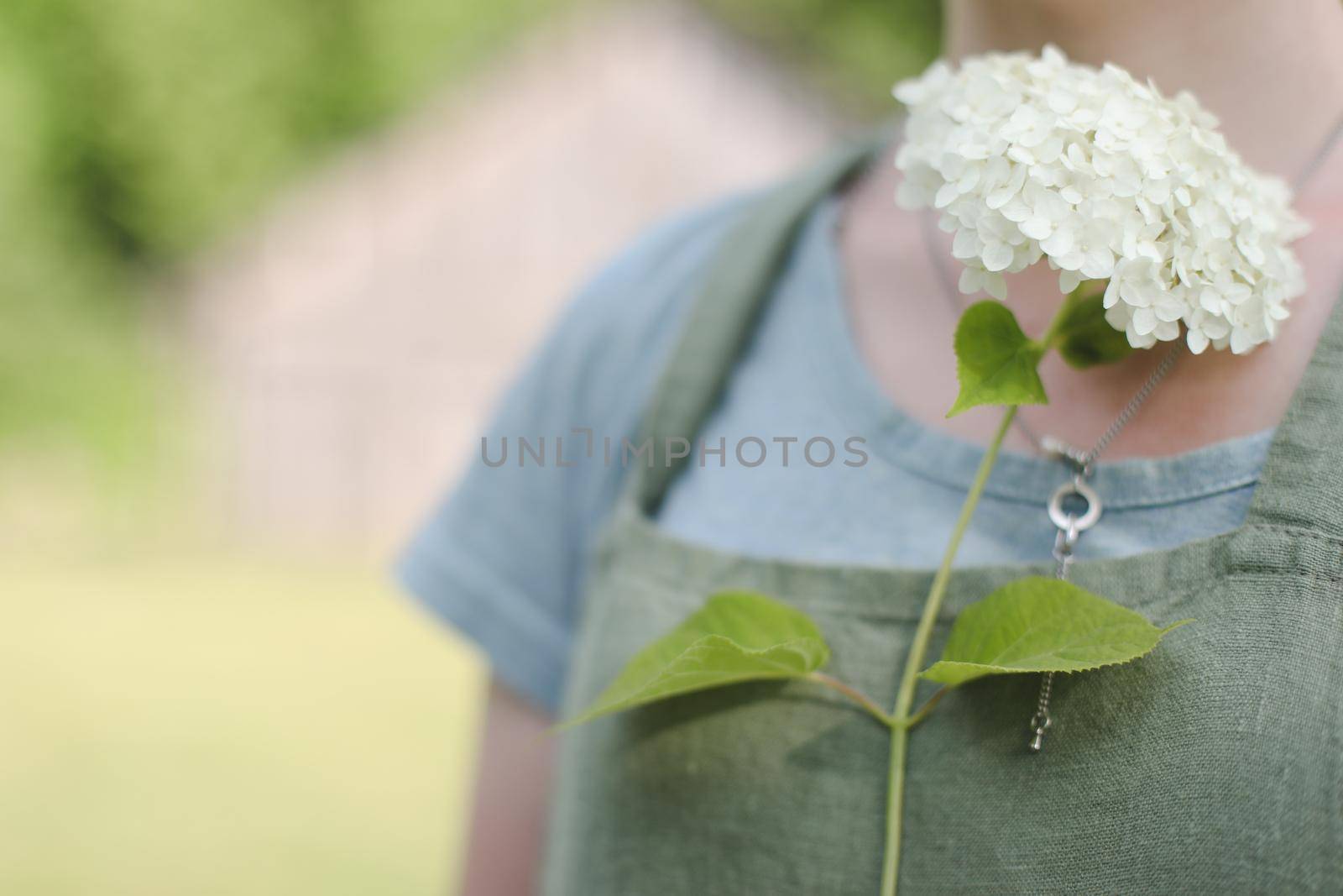 young woman in apron holding flowers in the garden in summer. gardening and profession concept