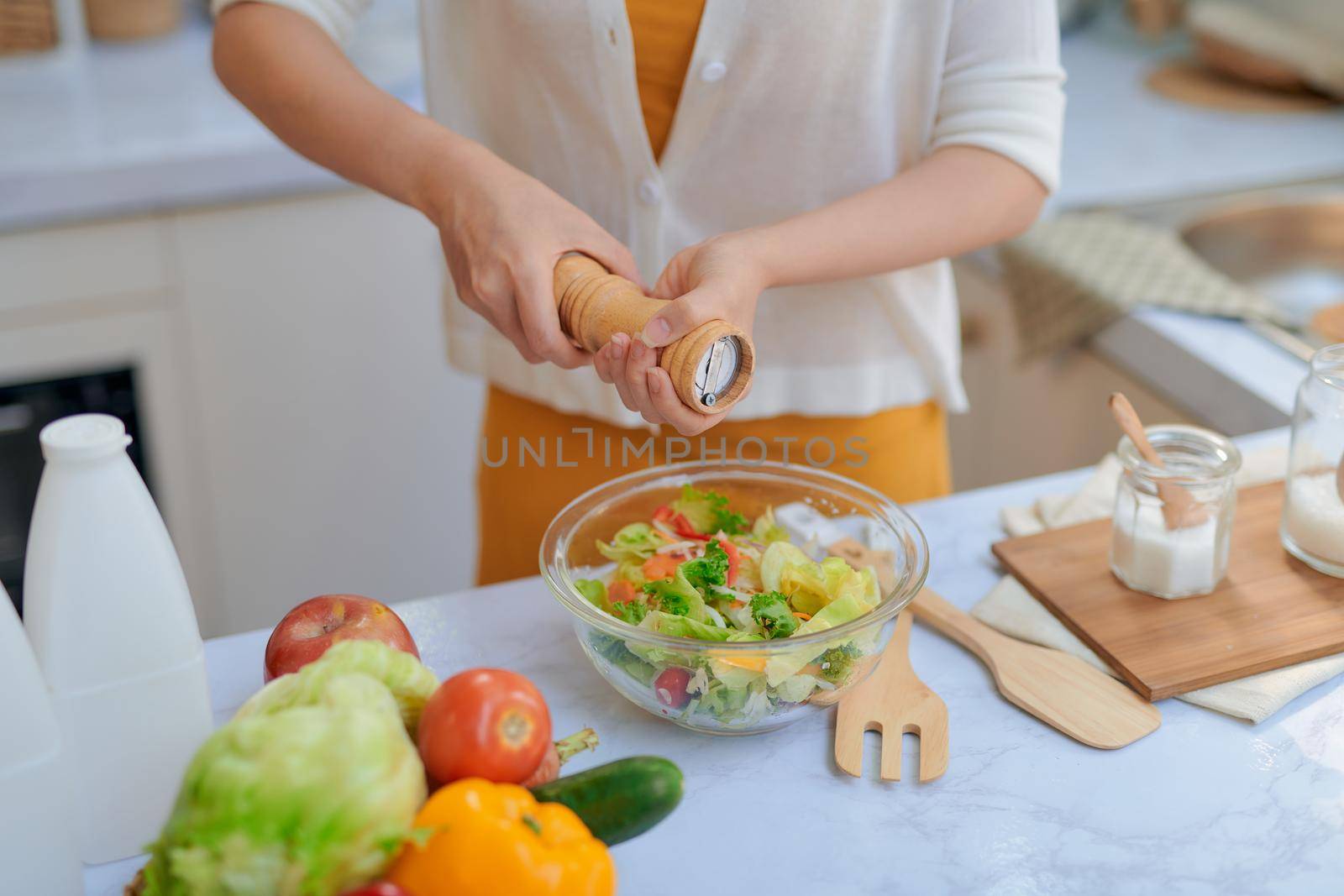 Pretty young woman chef putting salt in a salad