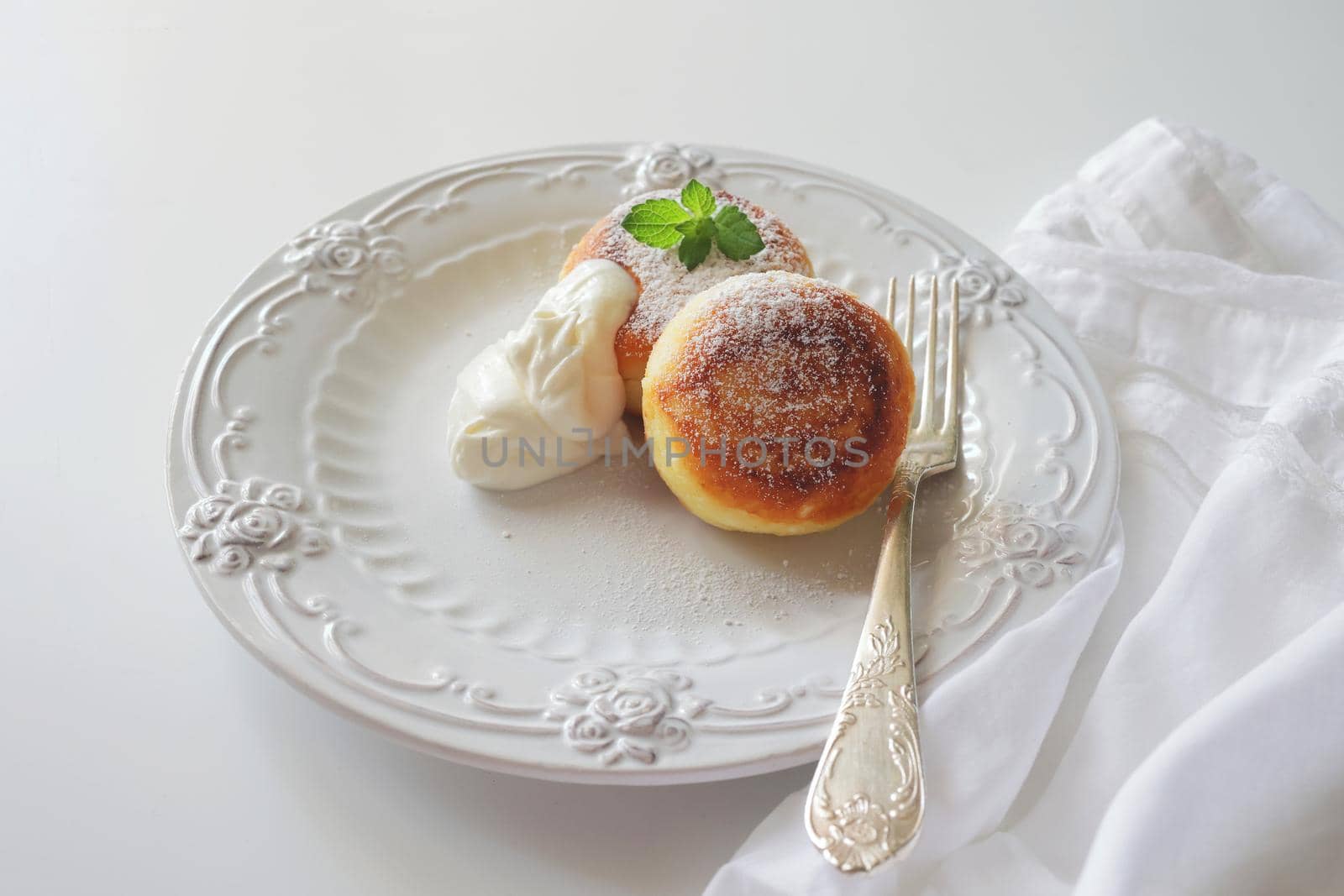 cheesecakes breakfast or dessert syrniki, curd cottage cheese pancakes. Cottage cheese pancakes, syrniki, ricotta fritters on white ceramic plate. Healthy and delicious morning breakfast. White background. Copy space for text, food background