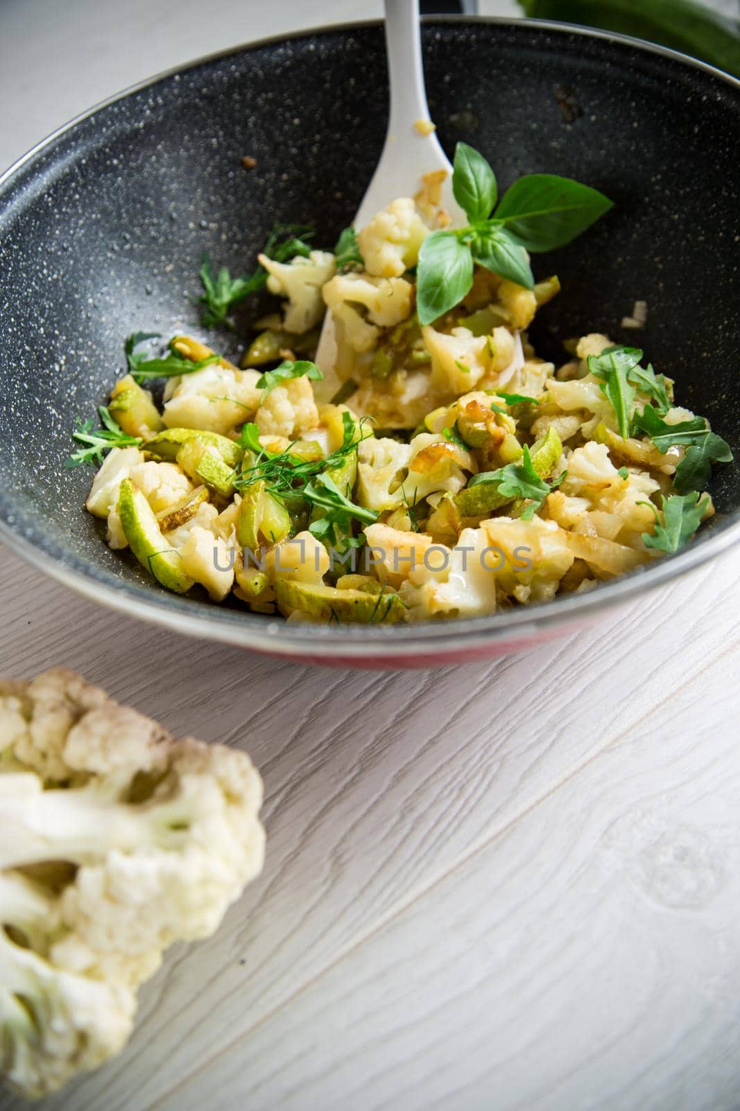cauliflower fried with zucchini and vegetables in a pan with herbs